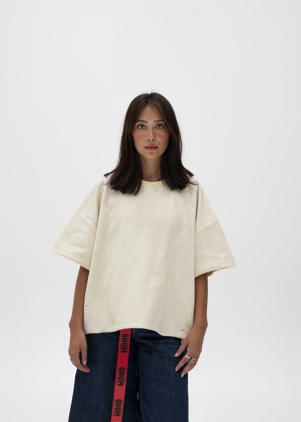 Model in the cream cropped fleece tee and dark denim with a GHUM webbing belt