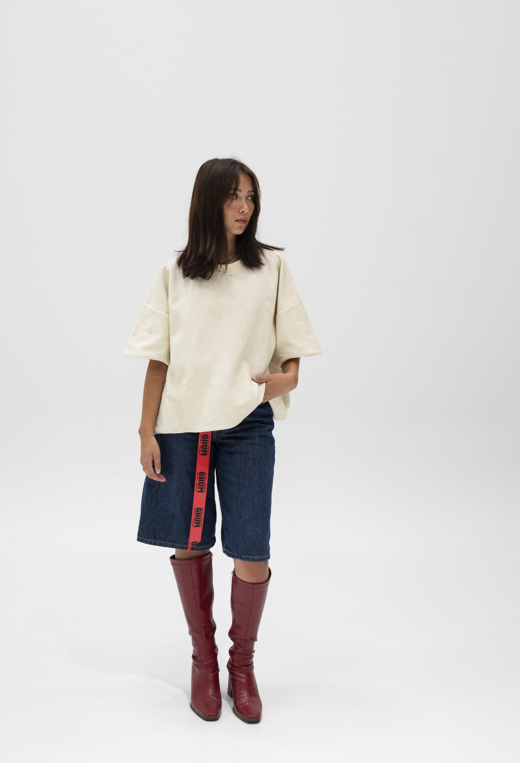 Full length shot of the cream cropped tee with denim shorts and red boots