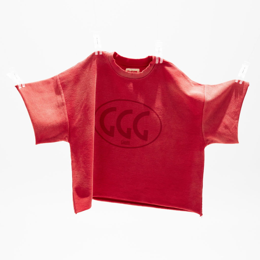 Red cropped fleece tee on a hanger showing the tonal GGG oval print