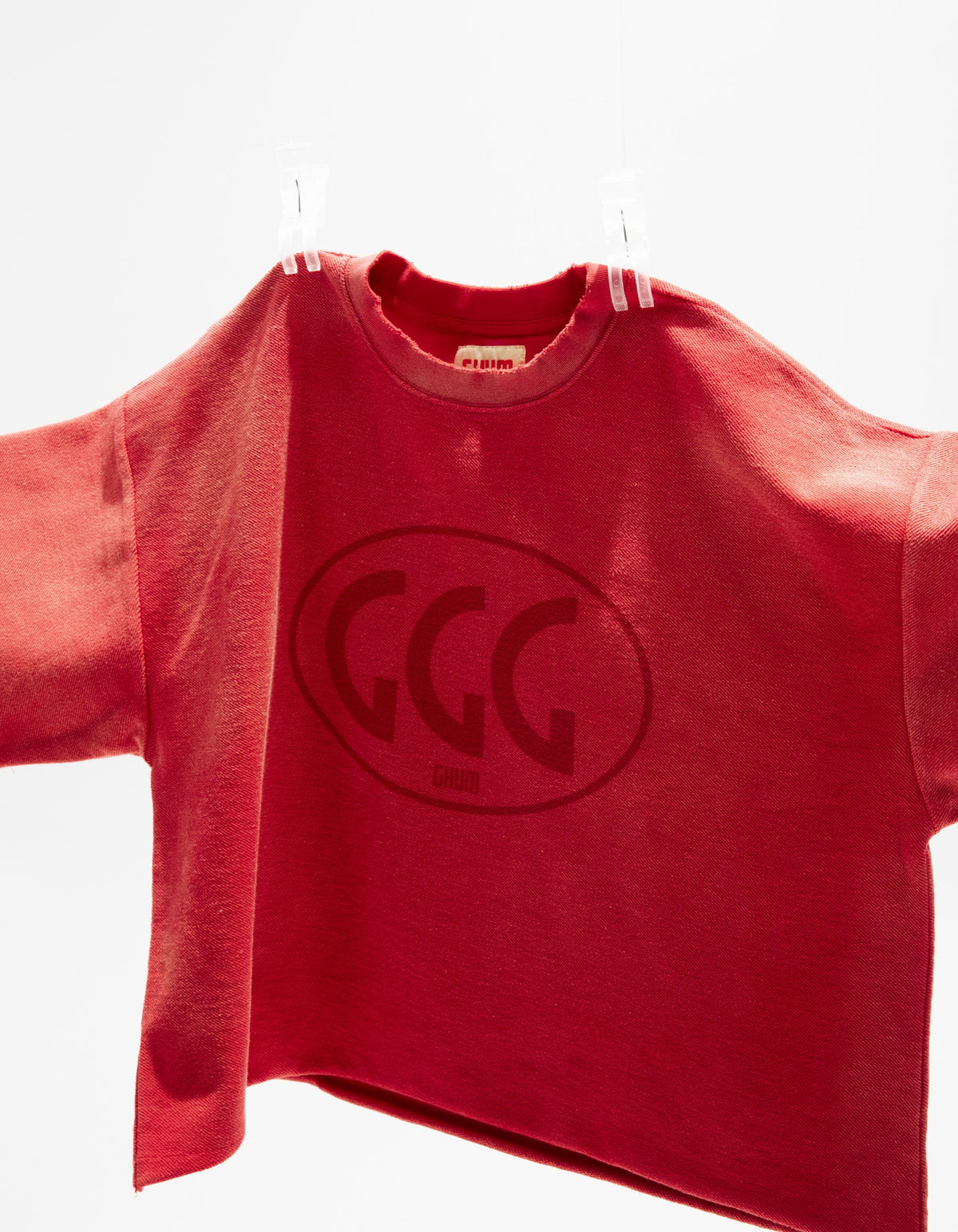 Red cropped tee laid open on a hanger, boxy cut and dropped shoulders